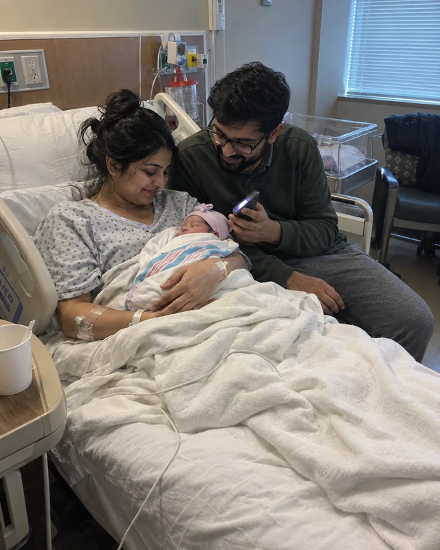 New parents in a hospital room smile down at their newborn while the father plays a lullaby on his phone (AI photo, fictional people)