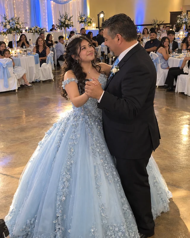 A fifteen-year-old girl in a pale blue ball gown waltzes with her father in a dark suit at her quinceañera while family watches (AI photo, fictional people)